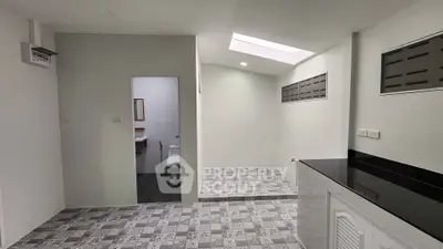 Modern minimalist interior with skylight and tiled flooring, featuring a compact bathroom and sleek kitchen area.