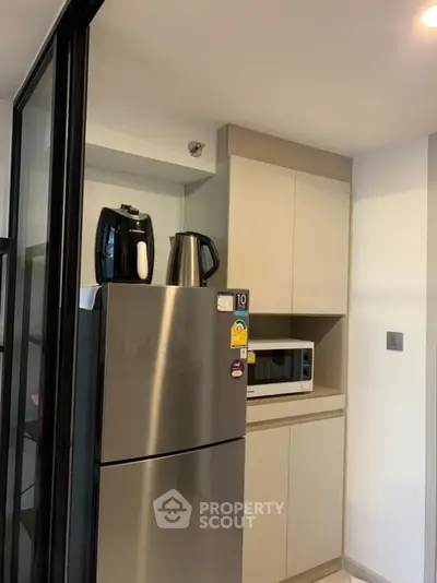 Modern kitchen with stainless steel fridge, microwave, and sleek cabinetry