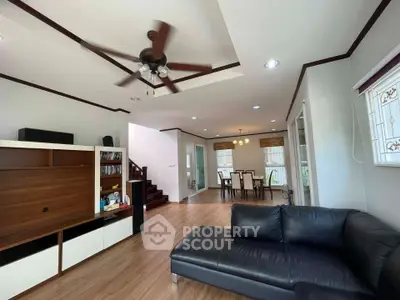 Spacious living room with modern decor and open dining area, featuring a ceiling fan and sleek furniture.