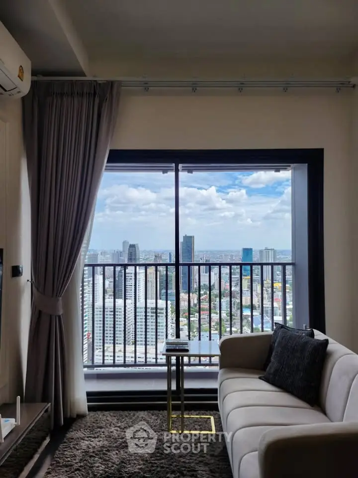 Modern living room with stunning city view from high-rise balcony, featuring elegant decor and cozy seating.