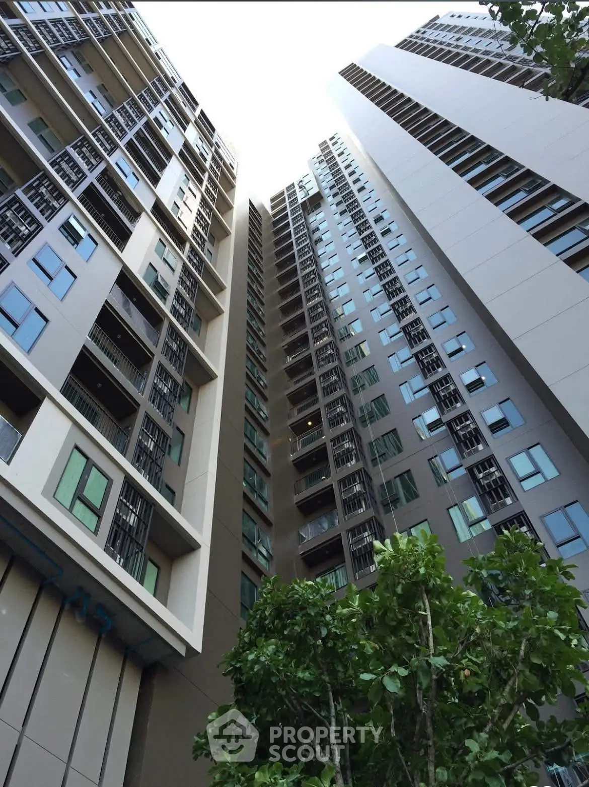 Modern high-rise residential building with sleek architecture and lush greenery.