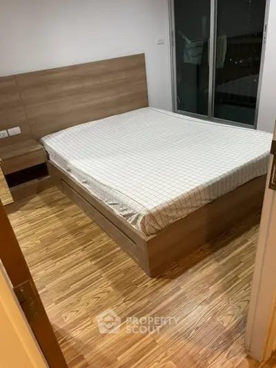 Spacious bedroom with wooden flooring and modern bed frame, perfect for a cozy retreat.