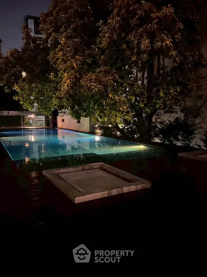 Luxurious night view of a serene outdoor pool surrounded by lush greenery, perfect for relaxation.