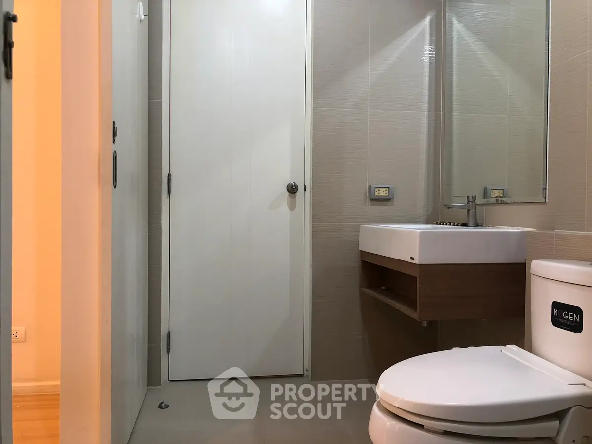 Modern bathroom with sleek fixtures and neutral tones, featuring a stylish sink and toilet.
