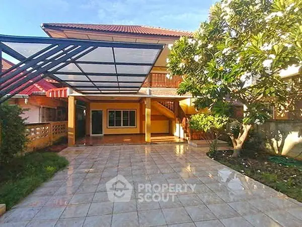 Charming two-story home with spacious tiled patio and lush garden, perfect for outdoor living.