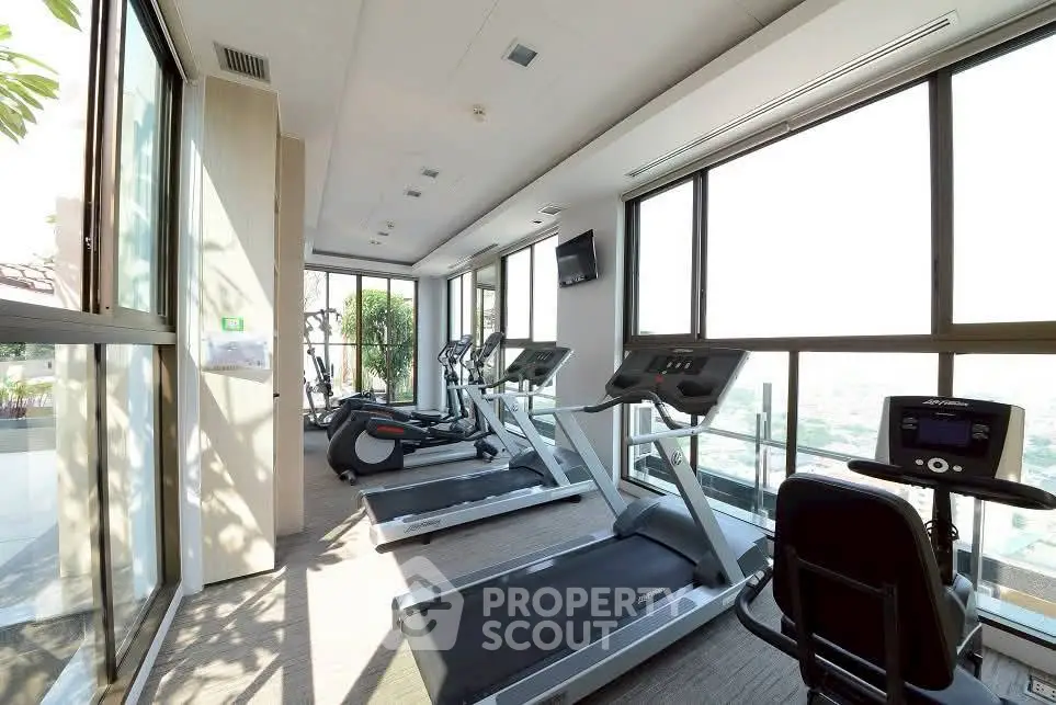 Spacious gym with modern equipment and panoramic city views, perfect for fitness enthusiasts.