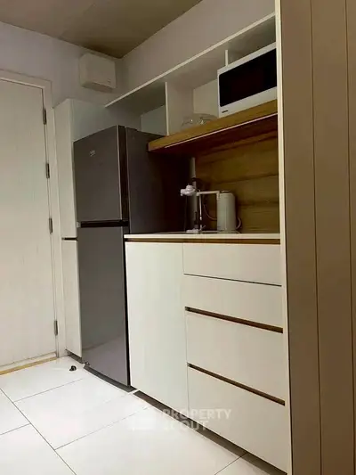 Modern kitchen with sleek cabinetry, stainless steel fridge, and microwave, perfect for urban living.
