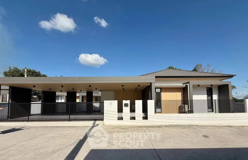 Modern single-story house with sleek design and spacious driveway under clear blue sky.