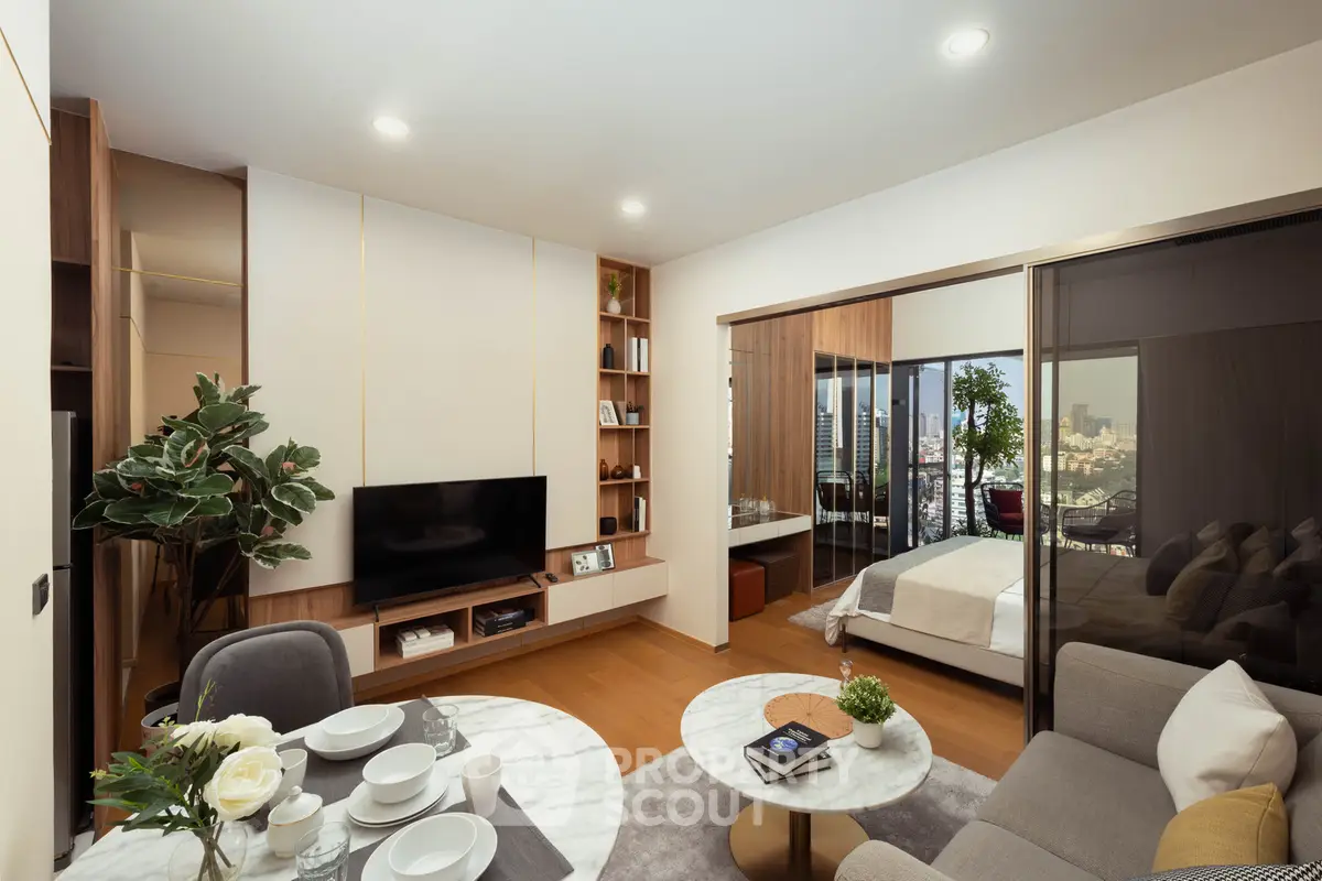 Modern open-plan living room with dining area and bedroom, featuring elegant decor and city views.
