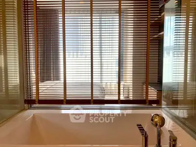 Luxurious bathroom with modern bathtub and stylish blinds offering a glimpse into a cozy bedroom.