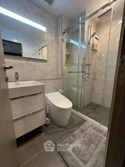 Modern bathroom with sleek design, featuring a glass shower enclosure and contemporary fixtures.