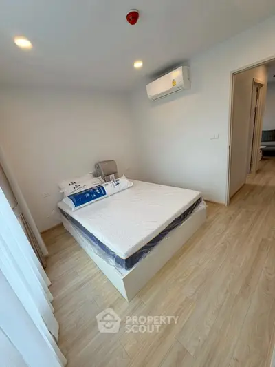 Modern bedroom with wooden flooring and air conditioning in a stylish apartment.