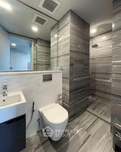Luxurious modern bathroom with sleek gray marble design and spacious shower area.