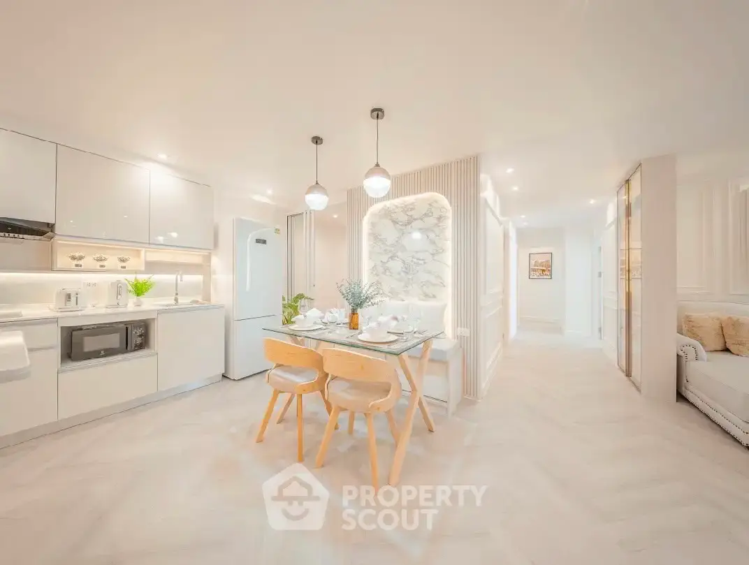 Modern open-plan kitchen and dining area with sleek white cabinetry and elegant lighting.
