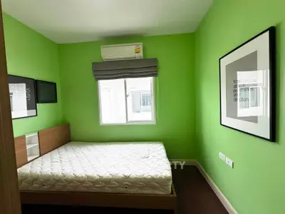 Bright bedroom with green walls, modern artwork, and air conditioning, perfect for a cozy retreat.