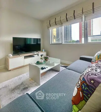 Modern living room with large TV and city view, featuring stylish decor and comfortable seating.