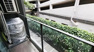 Modern balcony with glass railing overlooking lush greenery and urban surroundings.