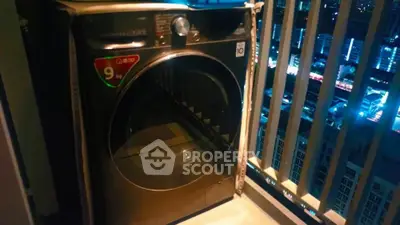 Modern washing machine on high-rise balcony with city night view