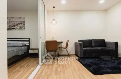 Modern studio apartment with cozy living area and bedroom separated by sliding glass door.