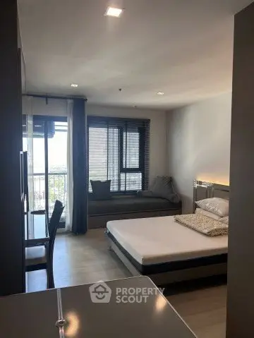 Modern bedroom with large windows and cozy seating area, perfect for relaxation.