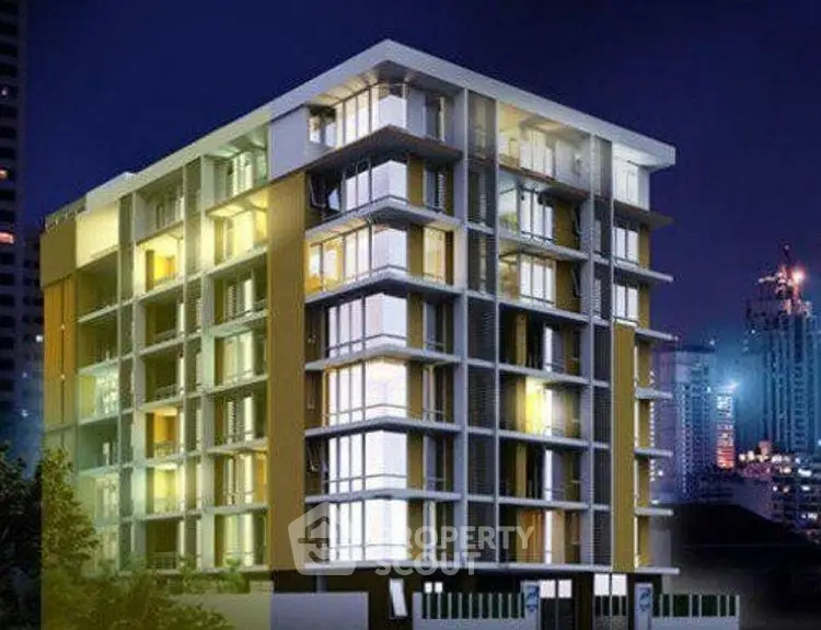 Modern multi-story apartment building with illuminated windows at night in urban setting.
