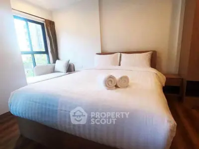 Cozy bedroom with large window and modern furnishings in a stylish apartment.