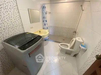 Spacious bathroom with washing machine and modern fixtures.