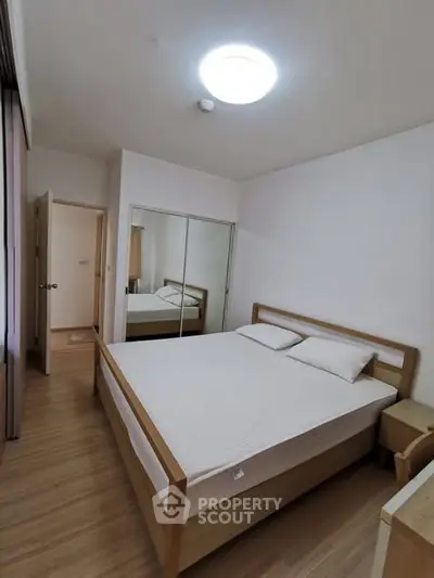 Spacious bedroom with wooden flooring and mirrored closet doors