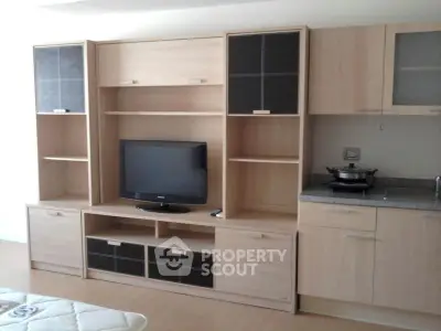 Modern living room with sleek entertainment center and compact kitchen area.