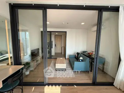 Modern living room with glass sliding doors, stylish furniture, and wooden flooring in a contemporary apartment.