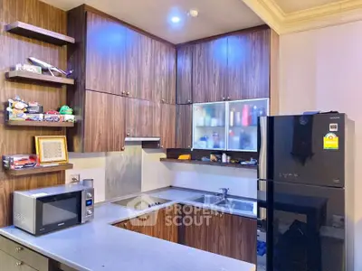Modern kitchen with sleek wooden cabinets and black appliances in a cozy apartment.