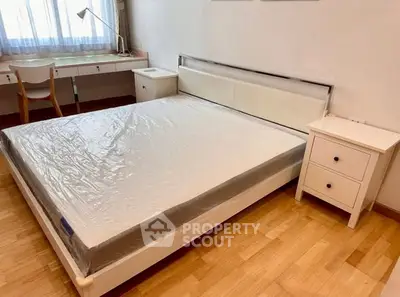 Spacious bedroom with modern furniture and natural light, featuring a large bed and study area.