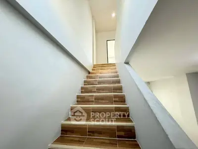 Modern staircase with wooden steps and white walls in a contemporary home interior.