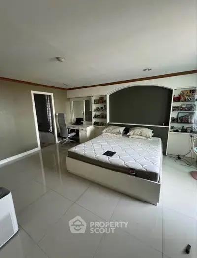 Spacious bedroom with modern decor and built-in shelves, perfect for comfort and style.