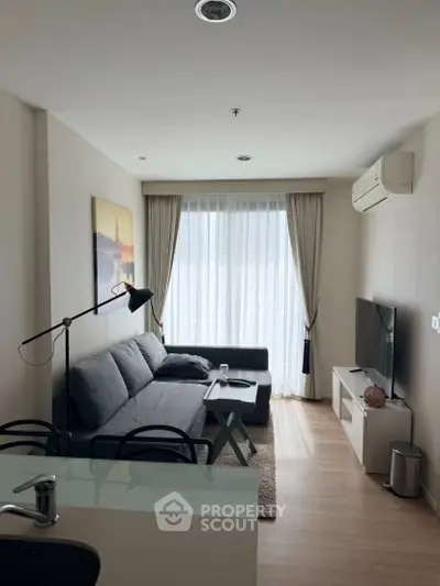 Modern living room with sleek furniture and natural light, featuring a cozy sofa and large TV.