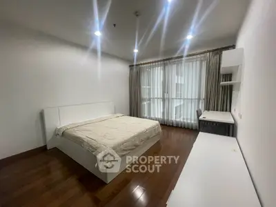 Spacious bedroom with modern furnishings and large window for natural light.