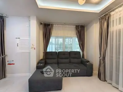 Spacious living room with modern gray sofa and elegant curtains, perfect for relaxation and entertainment.