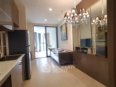 Modern living room with elegant chandelier and open kitchen layout in a stylish apartment.