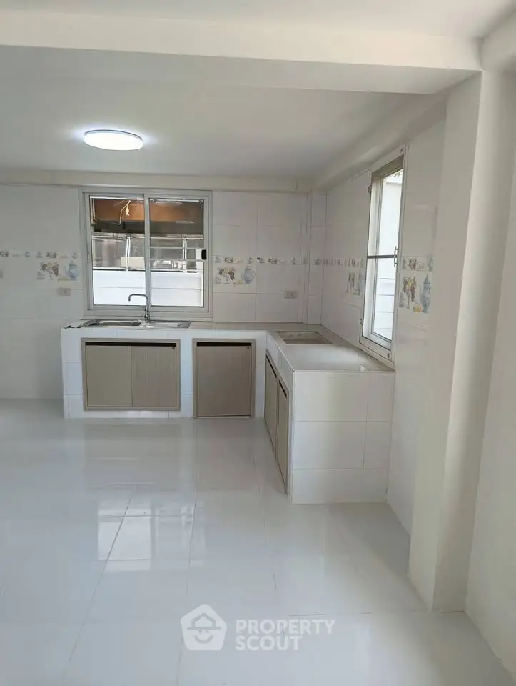 Spacious kitchen with dual sinks and large windows, perfect for culinary enthusiasts.