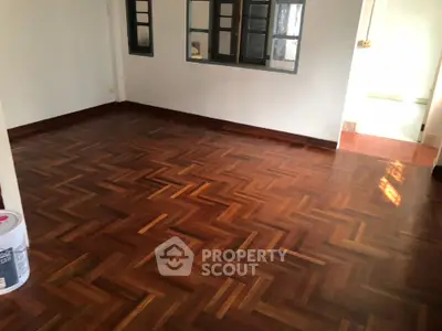Spacious room with elegant parquet flooring and large windows, perfect for a cozy living area.