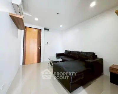 Modern living room with sleek black leather sofa and glass coffee table