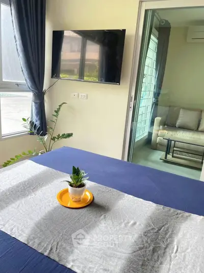 Modern bedroom with TV and balcony access, featuring stylish decor and natural light.