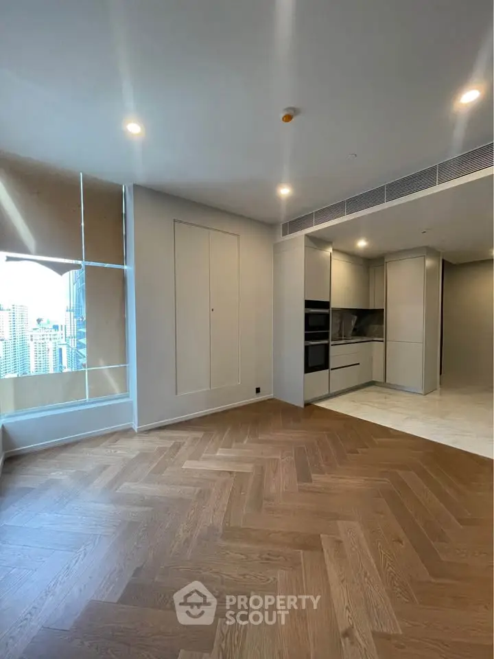Spacious modern living room with elegant wooden flooring and sleek kitchen design in urban apartment.