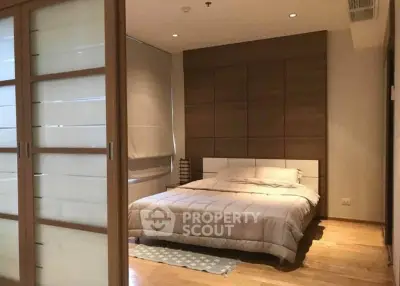 Modern bedroom with cozy lighting and wooden accents, featuring a comfortable bed and sliding doors.