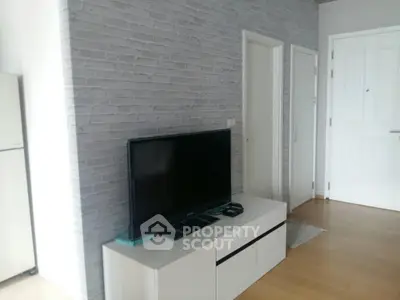 Modern living room with sleek TV setup and stylish brick accent wall.