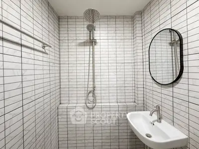 Modern minimalist bathroom with sleek shower and stylish sink in white tile design.