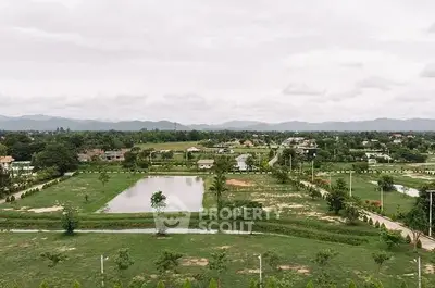 Scenic aerial view of lush green landscape with ponds and distant mountains, ideal for real estate development.