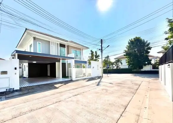 Modern two-story house with spacious driveway and sunny exterior in a serene neighborhood.