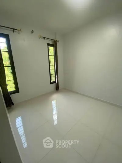 Spacious empty bedroom with large windows and tiled flooring, perfect for customization.