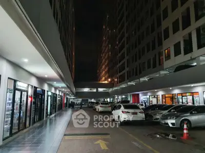Modern commercial building exterior with parking area at night, showcasing vibrant city life.